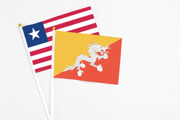 Bhutan and Liberia stick flags on white background. High quality fabric, miniature national flag. Peaceful global concept.White floor for copy space.