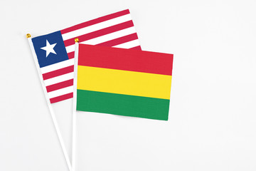 Bolivia and Liberia stick flags on white background. High quality fabric, miniature national flag. Peaceful global concept.White floor for copy space.