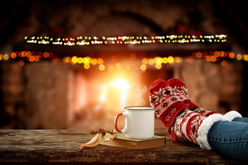 Blurred background of chrsitmas fireplace.Orange color of warm light of fire.Woman legs with socks...