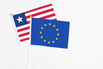 European Union and Liberia stick flags on white background. High quality fabric, miniature national flag. Peaceful global concept.White floor for copy space.