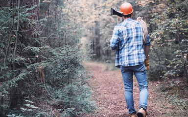 Male lumberjack in the forest. A professional woodcutter inspects trees for felling.