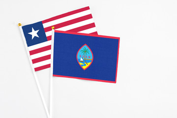 Guam and Liberia stick flags on white background. High quality fabric, miniature national flag. Peaceful global concept.White floor for copy space.