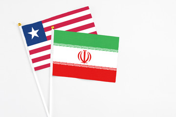 Fototapeta na wymiar Iran and Liberia stick flags on white background. High quality fabric, miniature national flag. Peaceful global concept.White floor for copy space.