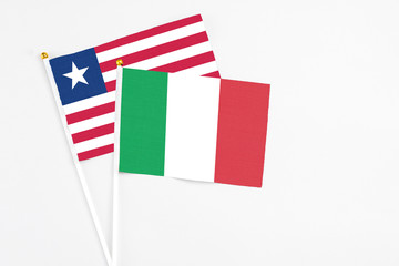 Italy and Liberia stick flags on white background. High quality fabric, miniature national flag. Peaceful global concept.White floor for copy space.