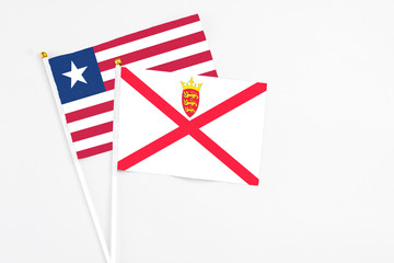 Fototapeta premium Jersey and Liberia stick flags on white background. High quality fabric, miniature national flag. Peaceful global concept.White floor for copy space.