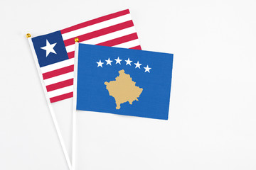 Kosovo and Liberia stick flags on white background. High quality fabric, miniature national flag. Peaceful global concept.White floor for copy space.
