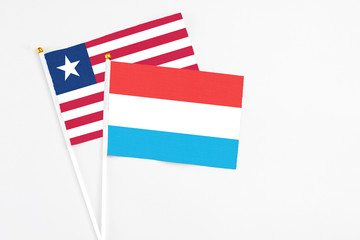 Luxembourg and Liberia stick flags on white background. High quality fabric, miniature national flag. Peaceful global concept.White floor for copy space.