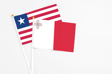 Malta and Liberia stick flags on white background. High quality fabric, miniature national flag. Peaceful global concept.White floor for copy space.