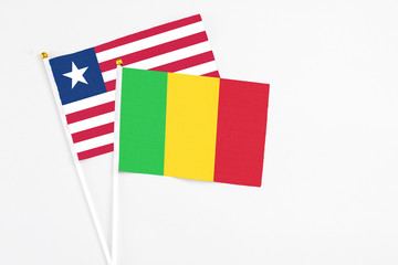 Mali and Liberia stick flags on white background. High quality fabric, miniature national flag. Peaceful global concept.White floor for copy space.