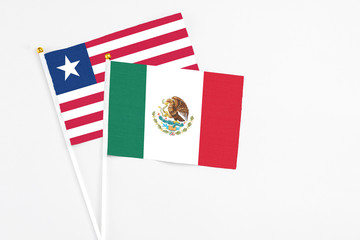 Mexico and Liberia stick flags on white background. High quality fabric, miniature national flag. Peaceful global concept.White floor for copy space.