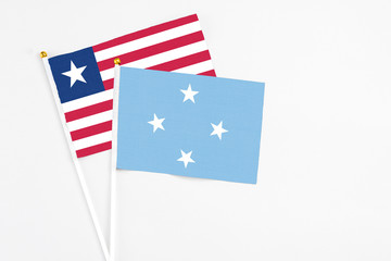 Micronesia and Liberia stick flags on white background. High quality fabric, miniature national flag. Peaceful global concept.White floor for copy space.