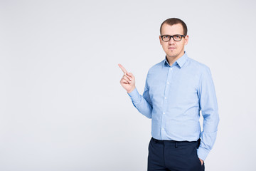 portrait of young businessman pointing at something over gray background