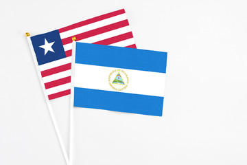 Nicaragua and Liberia stick flags on white background. High quality fabric, miniature national flag. Peaceful global concept.White floor for copy space.