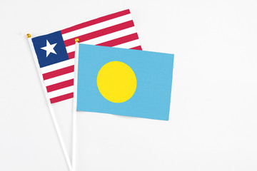 Palau and Liberia stick flags on white background. High quality fabric, miniature national flag. Peaceful global concept.White floor for copy space.