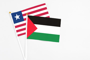 Palestine and Liberia stick flags on white background. High quality fabric, miniature national flag. Peaceful global concept.White floor for copy space.