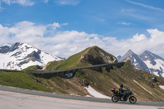 Mountain pass Fuscher Torl, view point on Grossglockner High Alpine Road, Austria. Sunny summer day, snowy peaks, top mountains, motorcyclist in action, biker driver, ride.