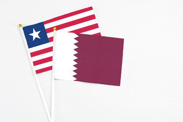 Qatar and Liberia stick flags on white background. High quality fabric, miniature national flag. Peaceful global concept.White floor for copy space.