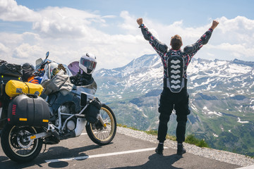 A motorcycle traveler is happy arrived at his destination. Conquering the top of the mountain,...