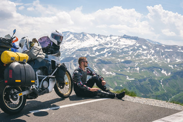A motorcycle traveler is sitting with his touring motorbike and lokk at distance. Copy space....