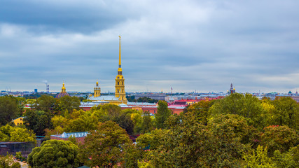 Fototapeta premium Beautiful panorama of the historic city center of St. Petersburg, Russia. Top view of the Peter and Paul Fortress and the cathedral with a golden spire. In the foreground is Alexander Park.