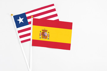 Spain and Liberia stick flags on white background. High quality fabric, miniature national flag. Peaceful global concept.White floor for copy space.