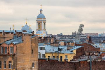 Fototapeta na wymiar The historical center of St. Petersburg, Russia. Top view on the roofs of old buildings and on the church. Above the houses rises the beautiful bell tower of Vladimir Cathedral. Sights of Petersburg.