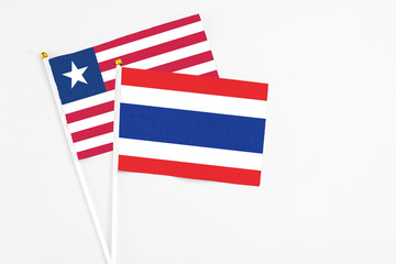 Thailand and Liberia stick flags on white background. High quality fabric, miniature national flag. Peaceful global concept.White floor for copy space.