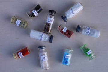 Scattered glass jars with different loose chemicals on the table.