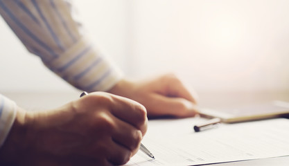 Business meeting. A man signs a contract. Male hand with pen makes notes in the office.