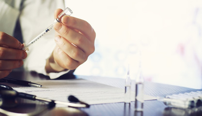 A man signs a medical document. Medical equipment on the table. Stethoscope and ampoules with...