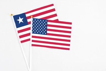 United States and Liberia stick flags on white background. High quality fabric, miniature national flag. Peaceful global concept.White floor for copy space.