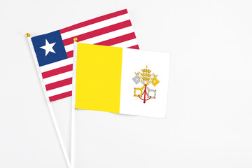 Vatican City and Liberia stick flags on white background. High quality fabric, miniature national flag. Peaceful global concept.White floor for copy space.