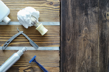 Shaving accessories on a wooden texture background. Tools. Disposable shaving machine, brush, foam and hazard razor.