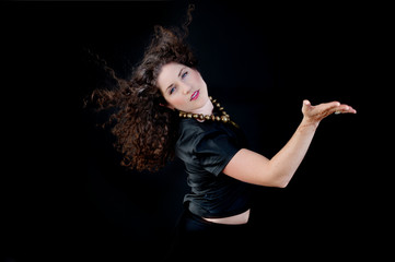 Stylish dancing woman wearing black on black background. 