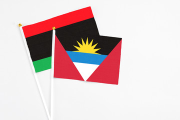 Antigua and Barbuda and Libya stick flags on white background. High quality fabric, miniature national flag. Peaceful global concept.White floor for copy space.