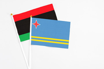 Aruba and Libya stick flags on white background. High quality fabric, miniature national flag. Peaceful global concept.White floor for copy space.