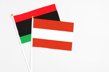 Austria and Libya stick flags on white background. High quality fabric, miniature national flag. Peaceful global concept.White floor for copy space.