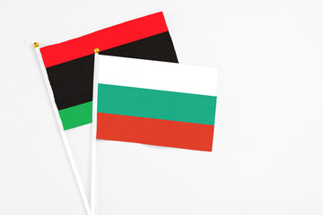 Bulgaria and Libya stick flags on white background. High quality fabric, miniature national flag. Peaceful global concept.White floor for copy space.