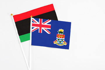 Fototapeta premium Cayman Islands and Libya stick flags on white background. High quality fabric, miniature national flag. Peaceful global concept.White floor for copy space.