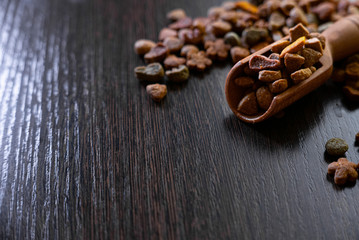 Healthy dry pet food in a wooden spoon on the black table