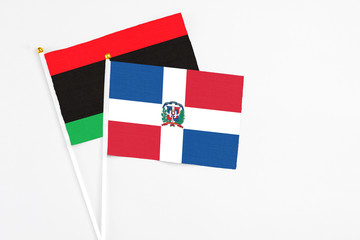 Dominican Republic and Libya stick flags on white background. High quality fabric, miniature national flag. Peaceful global concept.White floor for copy space.