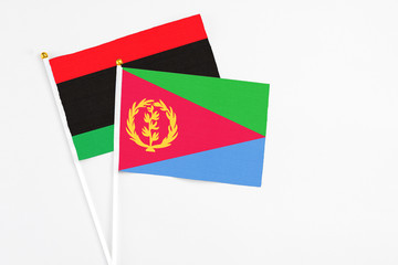 Eritrea and Libya stick flags on white background. High quality fabric, miniature national flag. Peaceful global concept.White floor for copy space.
