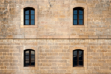 View of a facade with four windows on the walls of the former artillery fort Rapitán, in Jaca (Spain), with sunset light.