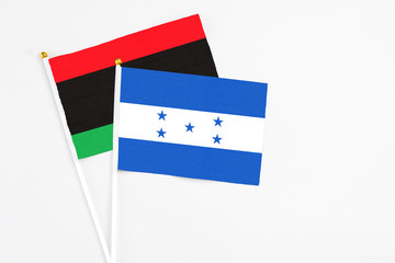 Honduras and Libya stick flags on white background. High quality fabric, miniature national flag. Peaceful global concept.White floor for copy space.