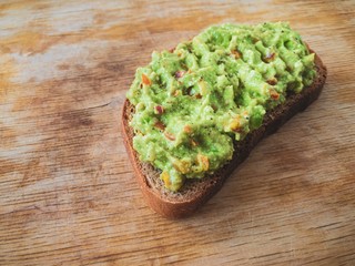 Simple sandwich with guacamole lying on a wooden surface