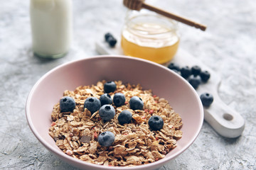  Healthy food background with homemade oatmeal granola or muesli, bottle of milk, honey and fresh berries for healthy morning breakfast. Selective focus on muesli.