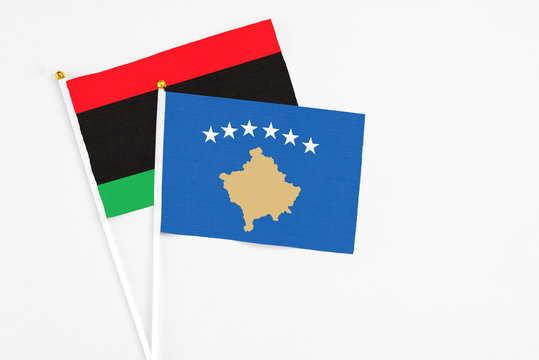 Kosovo and Libya stick flags on white background. High quality fabric, miniature national flag. Peaceful global concept.White floor for copy space.