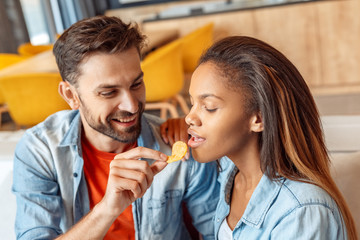 Young adult woman and man eating chips at home
