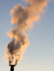 Smoke from the chimney of a house at dawn of the sun
