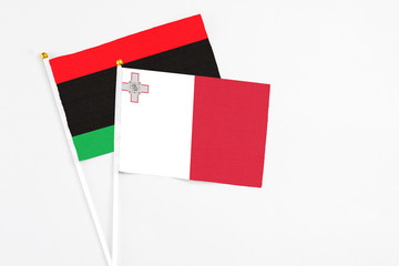 Malta and Libya stick flags on white background. High quality fabric, miniature national flag. Peaceful global concept.White floor for copy space.